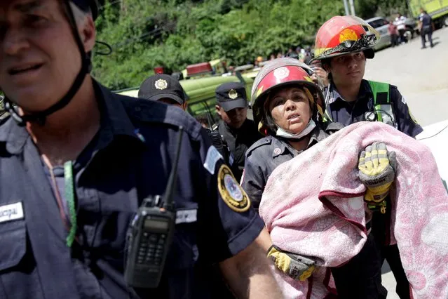A firefighter carries the body of a child retrieved from a mudslide in Santa Catarina Pinula, on the outskirts of Guatemala City, October 2, 2015. The collapse of a hillside onto a town on the edge of Guatemala City killed at least 26 people and left hundreds missing on Friday, as rescue crews desperately searched for survivors in homes buried by dirt and sludge. (Photo by Josue Decavele/Reuters)
