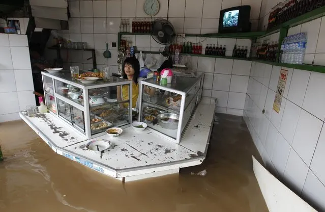 A woman stands in her food stall in the flooded business area in Jakarta January 17, 2013. Heavy monsoonal rains triggered severe flooding in large swathes of the Indonesian capital Jakarta on Thursday, with many government offices and businesses forced to closed because staff could not get to work. Weather officials warned the rains could get worse over the next few days and media reports said that thousands of people in Jakarta and its satellite cities had been forced to leave their homes because of the torrential downpours this week. (Photo by Enny Nuraheni/Reuters)