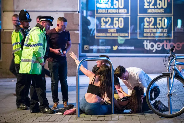 A woman reaches out her hand towards a police officer as another is tended to on the ground, on Withy Grove in Manchester, UK on September 11, 2016. (Photo by Joel Goodman/London News Pictures)