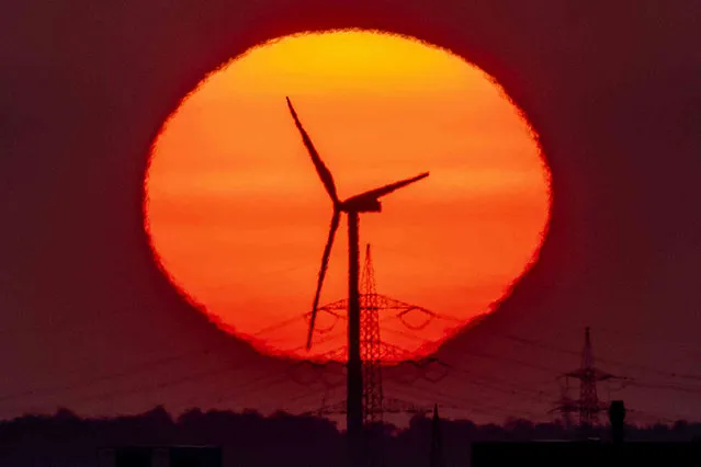 A wind turbine is pictured in front of the rising sun in Frankfurt, Germany, Monday, May 9, 2022. (Photo by Michael Probst/AP Photo)