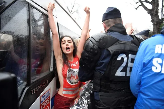 A member of feminist movement Femen group with lettering on her body reading “medically assisted procreation for all” gestures next to an anti riot police in Paris on January 21, 2018 during a “March for life” demonstration against abortion and medically assisted procreation. (Photo by Eric Feferberg/AFP Photo)