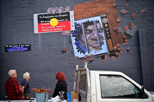 Artist Tim Guider (2-L) works on a mural titled “The subtle violence of social silence”, highlighting indigenous Australian deaths in custody, at Redfern in Sydney, Australia, 19 July 2020. (Photo by Joel Carrett/EPA/EFE)