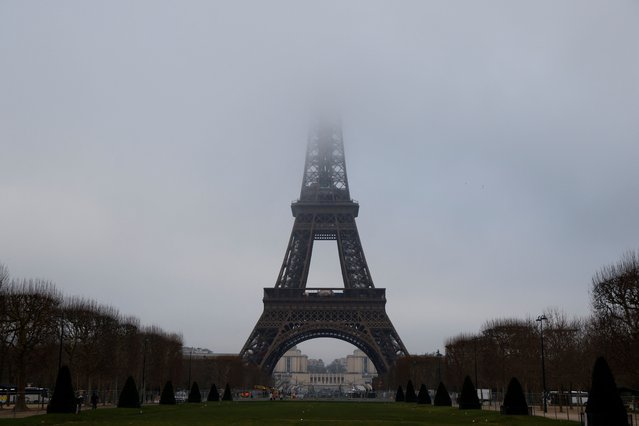 Tourists walk on the Trocadero Square in front of the Eiffel Tower in the fog in Paris, on Febuary 4, 2025. (Photo by Ludovic Marin/AFP Photo)