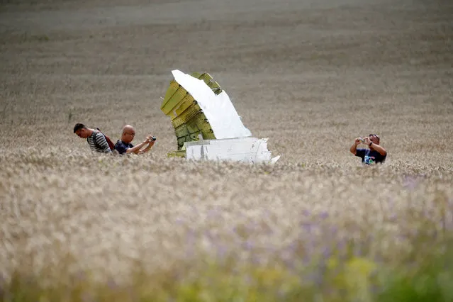 Malaysian air crash investigators take photos of the crash site of Malaysia Airlines Flight MH17, near the village of Hrabove (Grabovo), Donetsk region July 22, 2014. (Photo by Maxim Zmeyev/Reuters)