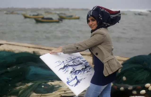 Palestinian artist Amna Al-Salmi tries to paint a scene at the Gaza seaport  during a windy day in Gaza City on November 24, 2014. UN peace envoy Robert Serry announced in early November that the temporary reconstruction mechanism for the war-torn Palestinian territory had begun operations, under the auspices of the newly formed Palestinian unity government, noting the urgency in providing cement and other materials to tens of thousands of damaged homes in Gaza ahead of winter. (Photo by Mohammed Abed/AFP Photo)