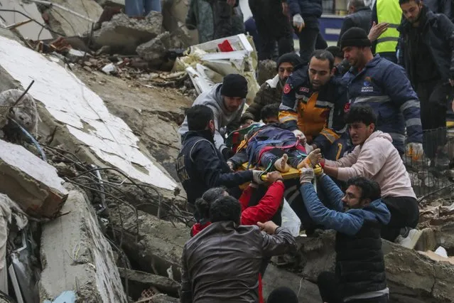 People and emergency teams rescue a person on a stretcher from a collapsed building in Adana, Turkey, Monday, February 6, 2023. A powerful quake has knocked down multiple buildings in southeast Turkey and Syria and many casualties are feared. (Photo by IHA agency via AP Photo)