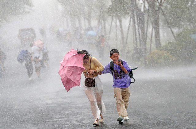 Tourists take shelter from the sudden heavy rain following the impact of Typhoon Danas on July 8, 2025 in Hangzhou, Zhejiang Province of China. East China's Zhejiang Province has elevated its typhoon emergency response to Level III at 10 a.m. on July 7 as Typhoon Danas, the fourth typhoon of this year, moves closer. (Photo by Lin Yunlong/Zhejiang Daily Press Group/VCG via Getty Images)