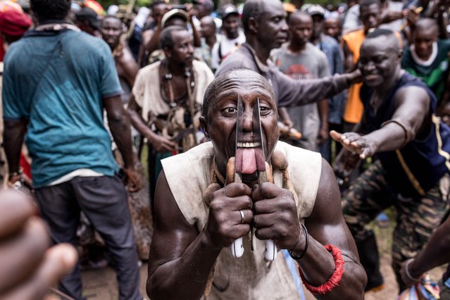 A man performs a sacred ritual cutting his tongue with a knife without drawing blood during the 2025 Jola Cultural Festival (Futampaff) in Thiobon, Cassamance region, Senegal, on August 6, 2025. The Festival is a significant cultural event for the Jola people, marking the transition from boyhood to manhood. As part of the rites, young initiates prepare to enter the sacred forest, a deeply spiritual journey guided by tradition and ancestral wisdom. The ceremony also teaches the importance of respecting elders and women, learning how to share, and embracing principles of success and community. (Photo by Muhamadou Bittaye/AFP Photo)