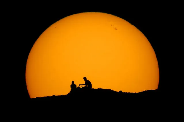 Hikers are silhouetted against the setting sun at Papago park Saturday, February 18, 2023, in Phoenix. (Photo by Charlie Riedel/AP Photo)