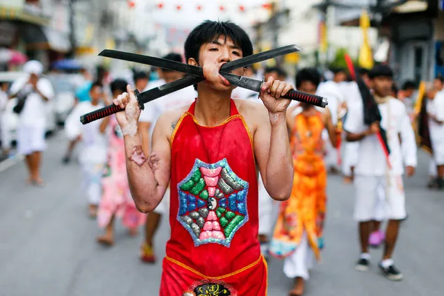 A devotee of the Chinese Ban Tha Rue shrine with blades piercing his face takes part in a procession celebrating the annual vegetarian festival in Phuket, Thailand October 5, 2016. (Photo by Jorge Silva/Reuters)