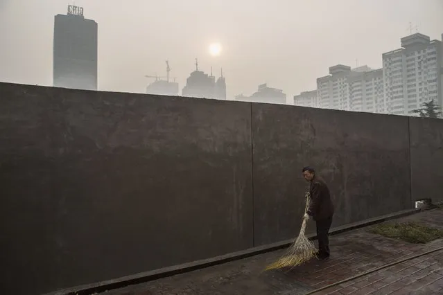 A Chinese worker sweeps the street as haze is seen on the skyline during a polluted morning on October 17, 2015 in Beijing, China. As a result of industry, the use of coal, and automobile emissions, the air quality in China's capital and other major cities is often many times worse than standards set by the World Health Organization.(Photo by Kevin Frayer/Getty Images)
