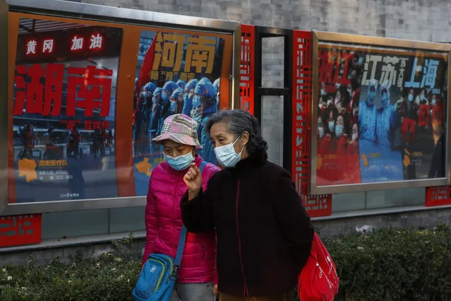 Women wearing face masks to help curb the spread of the coronavirus walk by posters tribute to the medical workers in different provincial on the frontlines against the COVID-19 at a park in Beijing, Monday, November 9, 2020. The coronavirus has hit another sobering milestone: more than 50 million positive cases worldwide since the pandemic began. (Photo by Andy Wong/AP Photo)