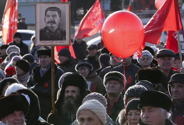 A man holds a board with an image of Soviet leader Joseph Stalin as activists and supporters of the Communist Party take part in a demonstration marking the anniversary of the 1917 Bolshevik revolution also known as known as the Great October Socialist Revolution in the Siberian city of Krasnoyarsk, Russia, November 7, 2015. (Photo by Ilya Naymushin/Reuters)