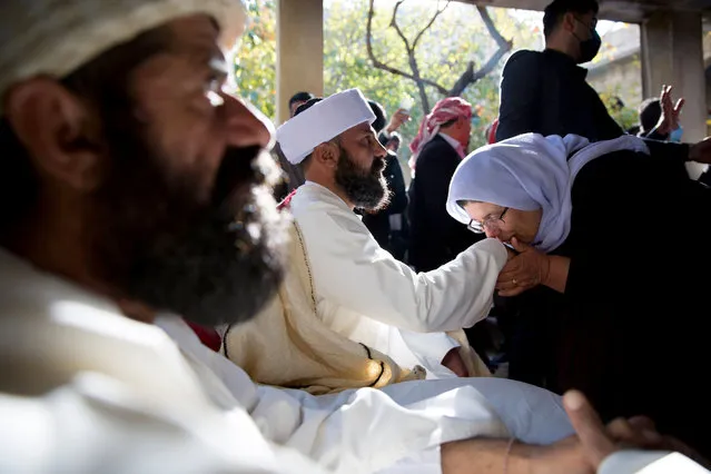 An elderly Yazidi woman kisses the hand of new Yazidi spiritual leader, also known as Baba Sheikh, Ali Elias Haji Nasir during the inauguration ceremony at Lalish Temple, south east of Duhok, Kurdistan region, Iraq, 18 November 2020. Sheikh Ali Elias Haji Nasir was appointed as the new spiritual leader of Yazidi minority group succeeding the late Khartu Hajji Ismael who died in early October at the age of 87. Nasir, 41, was chosen following consultations among family members, Yazidi tribes and the Yazidi Supreme Spiritual Council. The inauguration ceremony was held at the Lalish Temple, the holiest shrine of the Yazidis that was recently nominated on the UNESCO World Heritage List, and which contains the mausoleum of Sheikh Adi ibn Musafir, the 12th-century founder of Yazidism. There are over one million Yazidis worldwide, the majority of which live in Iraq, mainly in the Nineveh and Duhok governorates. The community was targeted by the Islamic State (IS) militants violence in Sinjar in 2014 forcing the displacement of thousands while women were forced into sexual slavery, trafficking and religious conversion. (Photo by Gailan Haji/EPA/EFE/Rex Features/Shutterstock)
