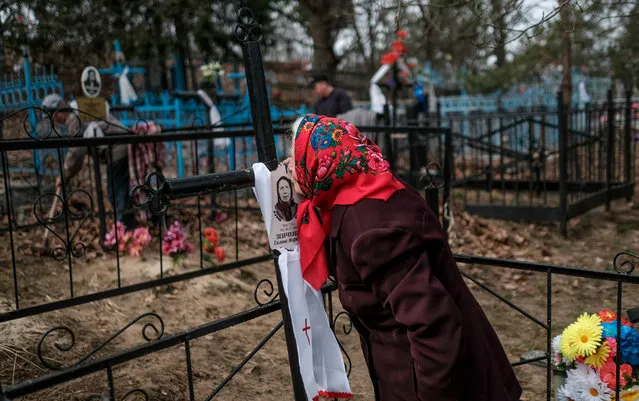 A woman kisses a picture of a departed woman at a cemetery in the village of Orevichi, inside the exclusion zone around the Chernobyl nuclear reactor, some 390 km of Minsk, during Radunitsa day (Radonitsa, Radonica or Radunica), the Russian Orthodox Church commemoration of the departed, on April 17, 2018. The explosion at reactor number four of the Chernobyl power plant on April 26, 1986 sent radioactive fallout into the atmosphere that spread across Europe, particularly contaminating Belarus, Ukraine and Russia. (Photo by Maxim Malinovsky/AFP Photo)