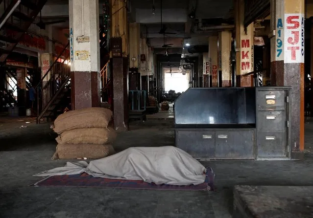A worker sleeps inside an empty vegetable wholesale market during a nationwide strike to protest against newly passed farm bills in Mumbai, India, December 8, 2020. (Photo by Francis Mascarenhas/Reuters)