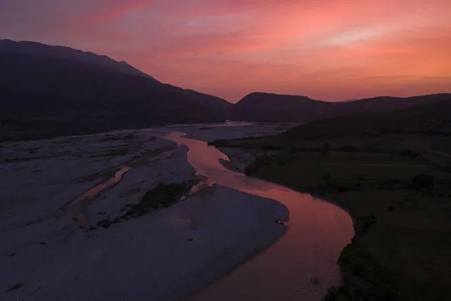 The sun sets behind the Vjosa River near Tepelene, Albania. Officials on Monday, June 13, 2022. The Albanian government on Wednesday, March 15, 2023 formally designated the Vjosa River and its tributaries a national park, starting with an investment of some $80 million (75 million Euro) to stop pouring wastewater into the river. (Photo by Felipe Dana/AP Photo)