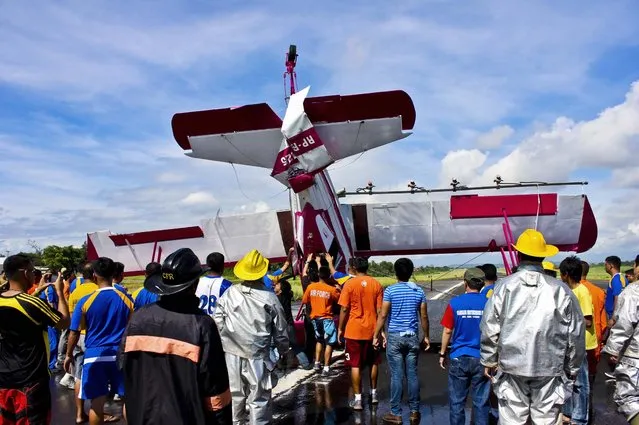 Rescue personnel remove a Cessna plane from the runway after it crashed shortly after taking off at Davao city International Airport in southern Philippines, on May 24, 2013. The plane took off to spray pesticides over banana plantations when it encountered engine trouble causing it to crash on the runway. The pilot was unharmed. (Photo by Bom Dy/Associated Press)