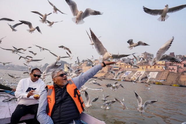 Indian tourists feed Siberian gulls from a boat on the River Ganges early morning in Varanasi, India Sunday, November 16, 2025. (Photo by Rajesh Kumar Singh/AP Photo)
