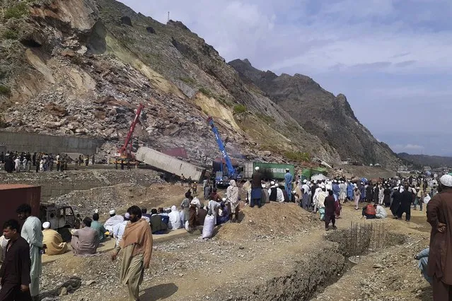 Local residents gather as authorities use heavy machines to search survivors and clear the rubble following a landslide struck a highway near the Torkham border town, Pakistan, Tuesday, April 18, 2023. A massive landslide struck a key highway near the Torkham border town in northwestern Pakistan before dawn Tuesday, burying several trucks and injuring some people, police and rescue officials said. (Photo by Muhammad Sajjad/AP Photo)