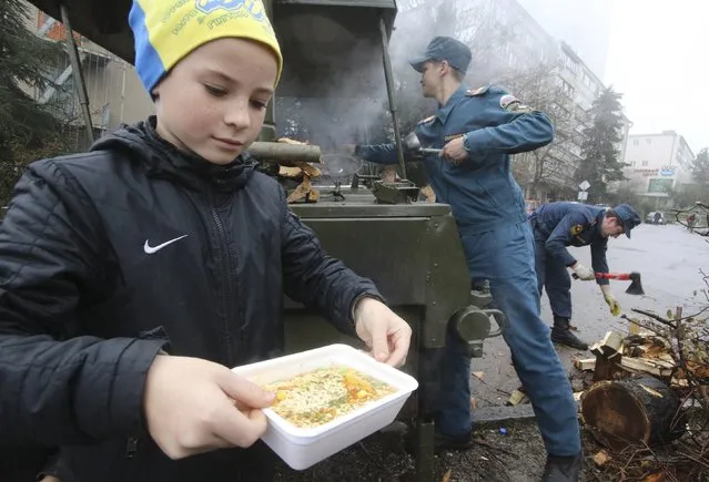 A boy carries a container with soup as he visits a mobile station, opened and operated by members of the Russian Emergencies Ministry to lend support and to distribute hot meals among local residents due to power cuts in the settlement of Massandra, Crimea, November 27, 2015. (Photo by Pavel Rebrov/Reuters)