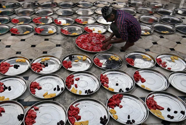 A Muslim man prepares plates of food for Iftar (breaking fast) meals inside a mosque during the holy fasting month of Ramadan in Ahmedabad, India, May 27, 2018. (Photo by Amit Dave/Reuters)
