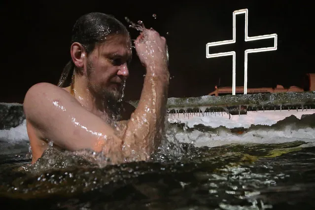 A man takes a dip in the icy waters of the Izhora River at St Trinity Cathedral in Kolpino in St Petersburg, Russia on January 18, 2021 on the eve of Epiphany. The temperature is –6°C (21.2°F). The Russian Orthodox Church celebrates the holiday according to the Julian calendar. (Photo by Peter Kovalev/TASS)