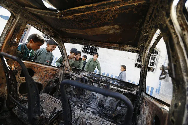 Boys look at a vehicle destroyed during a police raid on a hideout of al Qaeda militants in the Arhab region, north of the Yemeni capital Sanaa May 27, 2014. (Photo by Khaled Abdullah/Reuters)