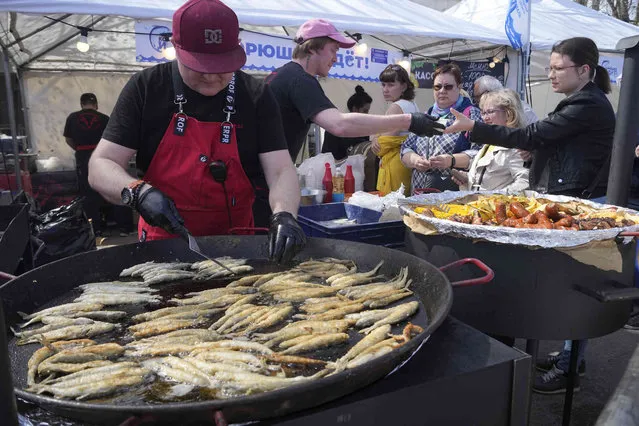 A cook fries smelt fish during a traditional smelt fish gastronomic festival in the city of Novaya Ladoga (New Ladoga), 125 km (77 miles) east of St. Petersburg, Russia, Saturday, May 13, 2023. In the northern Russian city Saint Petersburg smelt fish (known locally as koryushka) is known as a special local delicacy, famous for its “cucumber” smell. In April-May the smelt season opens up with many street vendors offering the fresh merchandise. (Photo by Dmitri Lovetsky/AP Photo)