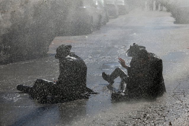 Protesters are hit with a water canon as ultra-Orthodox Jewish men protest against attempts to recruit men from the community, outside a military recruitment office in Jerusalem, on August 21, 2024. (Photo by Ammar Awad/Reuters)