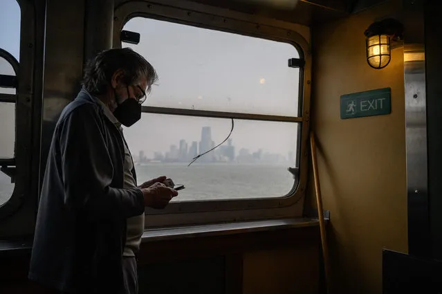 A passenger wearing a face mask rides the Staten Island Ferry past the Manhattan skyline during heavy smog in New York on June 6, 2023. Smoke from Canada’s wildfires has engulfed the Northeast and Mid-Atlantic regions of the US, raising concerns over the harms of persistent poor air quality. (Photo by Ed Jones/AFP Photo)