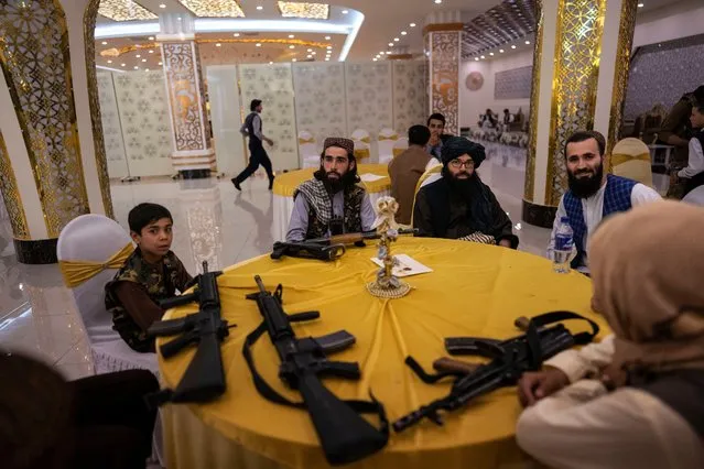 Taliban guards and guests sit at a table in the Imperial Continental wedding hall during a wedding in Kabul, Afghanistan, on Saturday, May 27, 2023. (Photo by Rodrigo Abd/AP Photo)