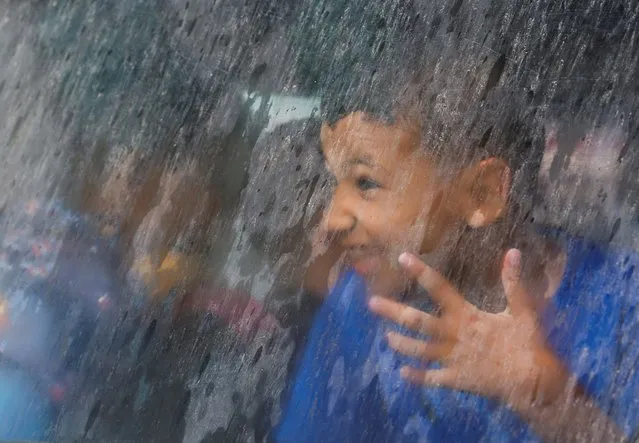 A Palestinian boy looks through a car window on a rainy day in Gaza City on June 13, 2023. (Photo by Mohammed Salem/Reuters)