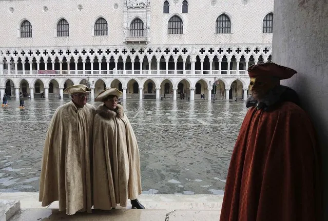 Masked revellers pose along the flooded St. Mark's Square during a period of seasonal high water and on the first day of carnival, in Venice February 1, 2015. (Photo by Stefano Rellandini/Reuters)
