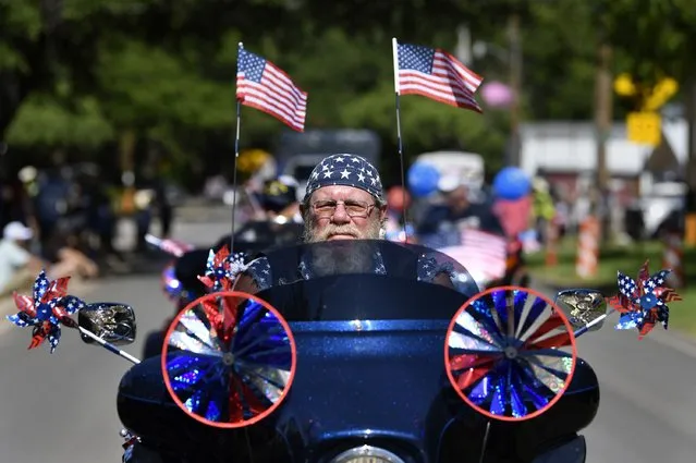 Flags and patriotic stars flutter and twirl as Dwane Tervooren rides with other motorcyclists during Tuesday's Independence Dayparade in Buffalo Gap, Texas Tuesday, July 4, 2023.  (Photo by Ronald W. Erdrich /The Abilene Reporter-News via AP Photo)