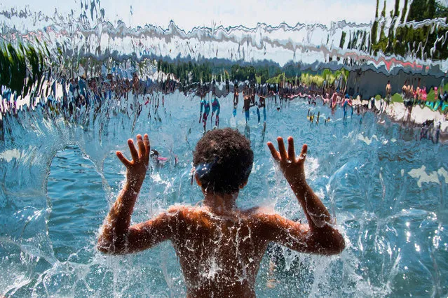 A child plays in the waterfall at Yards Park amid warm Summer temperatures in Washington, DC, July 19, 2018. (Photo by Jim Watson/AFP Photo)