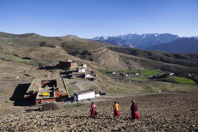 In this photograph taken on July 7, 2018, Indian Buddhist monks walk down from a hill overlooking Tnagyud Gompa monastery in Komik in Spiti Valley in the northern state of Himachal Pradesh. (Photo by Xavier Galiana/AFP Photo)