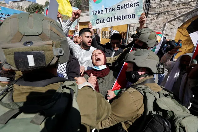 A Palestinian woman shouts slogans in front of Israeli troops during a protest against Israeli settlers, in Hebron, in the Israeli-occupied West Bank on February 26, 2021. (Photo by Mussa Qawasma/Reuters)