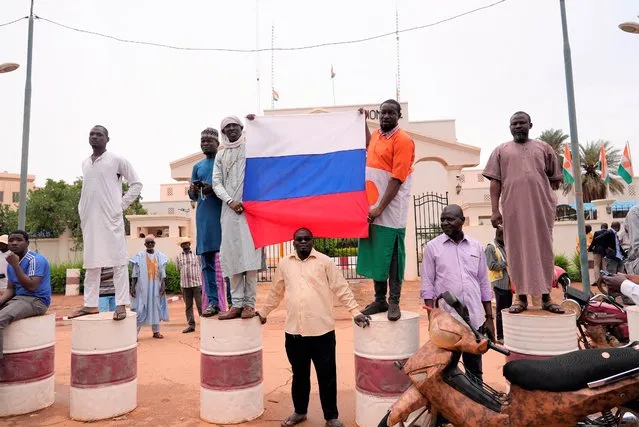 Supporters of mutinous soldiers hold a Russian flag as they demonstrate in Niamey, Niger, Thursday July 27 2023. Governing bodies in Africa condemned what they characterized as a coup attempt Wednesday against Niger's President Mohamed Bazoum, after members of the presidential guard declared they had seized power in a coup over the West African country's deteriorating security situation. (Photo by Sam Mednick/AP Photo)