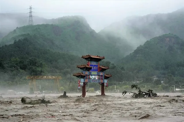 A traditional gate is seen inundated by flood waters in the Miaofengshan area on the outskirts of Beijing, Tuesday, August 1, 2023. Chinese state media report some have died and others are missing amid flooding in the mountains surrounding the capital Beijing. (Photo by Ng Han Guan/AP Photo)