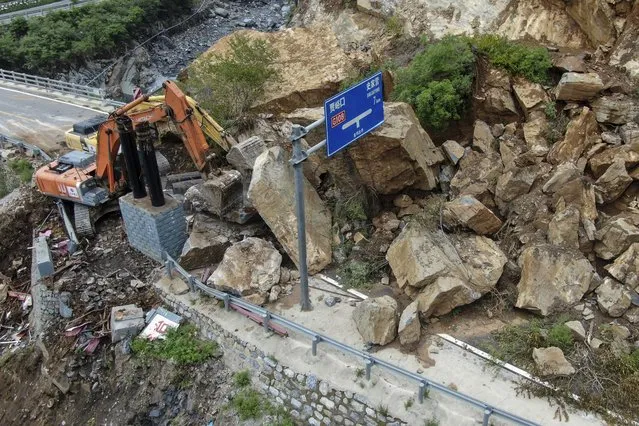 In this photo released by Xinhua News Agency, heavy machinery remove rocks fallen on a road in the aftermath of rainstorms in Shijiaying Town of Fangshan District on the outskirts of Beijing on Sunday, August 6, 2023. Multiple people including rescuers have been killed in recent flooding in China's capital, and many others are missing, officials said Wednesday, as much of the country's north remains threatened by unusually heavy rainfall. (Photo by Ju Huanzong/Xinhua via AP Photo)