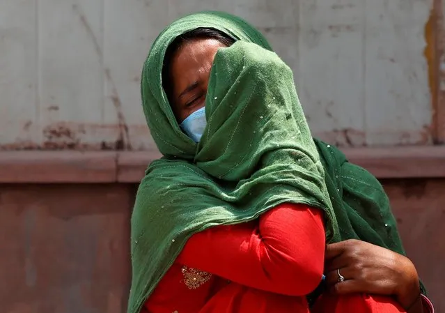 A woman mourns after her father died due to the coronavirus disease (COVID-19) outside a mortuary of a COVID-19 hospital in New Delhi, India, April 15, 2021. (Photo by Danish Siddiqui/Reuters)