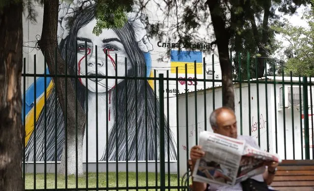 A Romanian elderly man reads a newspaper on a bench, with a painting on the Ukraine war theme displayed on the wall of Mihai Bravu Technical College building in the background, during the first day of the teachers' general strike, in Bucharest, Romania, 22 May 2023. About 150,000 teachers are striking across Romania in an ongoing dispute over pay and conditions, after the negotiations between the government and education workers trade union failed on 21 May. Romanian teachers called for the government to consider their demands for wage restoration, better working conditions and better wages for debutant teachers. The Federation of Education Trade Unions announced that the duration of the strike depends on the government's response to the teachers' requests, advising parents to keep their children at home. (Photo by Robert Ghement/EPA/EFE)