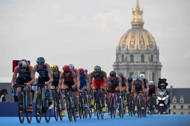 Triathlon athletes ride with The Hotel des Invalides in the background during the men's 2023 World Triathlon Olympic Games Test Event in Paris, on August 18, 2023. From August 17 to 20, 2023, Paris 2024 is organising four triathlon events to test several arrangements, such as the sports operations, one year before the Paris 2024 Olympic and Paralympic Games. The swim familiarisation event follows the cancellation on August 6 of the pre-Olympics test swimming competition due to excessive pollution which forced organisers to cancel the pre-Olympics event. (Photo by Bertrand Guay/AFP Photo)