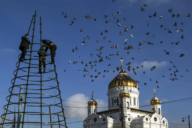 Municipal workers disassemble Christmas decorations in front of Christ the Savior Cathedral in Moscow, Thursday, January 21, 2016. (Photo by Pavel Golovkin/AP Photo)