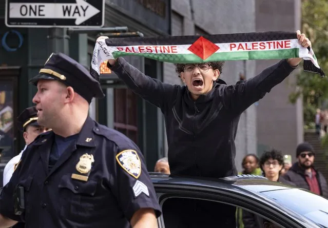 A Palestinian supporter passes by supporters of Israel gathered near the Israeli Consulate in New York, Monday, October 9, 2023, in the wake of an attack on Israel by Hamas militants. (Photo by Craig Ruttle/AP Photo)