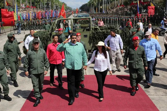Venezuela's President Nicolas Maduro (C) salutes as he arrives to a military parade, next to his wife and deputy of Venezuela's United Socialist Party (PSUV) Cilia Flores (centre R) and Venezuela's Defense Minister Vladimir Padrino Lopez (front row L) in Campo de Carabobo, Venezuela December 28, 2016. (Photo by Reuters/Miraflores Palace)