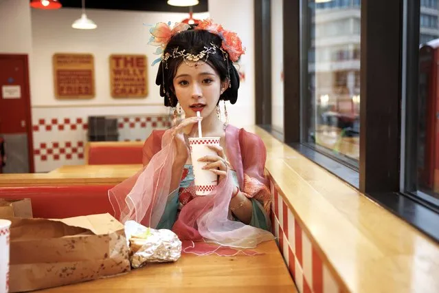 A Chinese girl in traditional dress eats her lunch in a Five Guys restaurant in between shooting videos for her Chinese social media account on October 18, 2023 in London, United Kingdom. (Photo by Dan Kitwood/Getty Images)