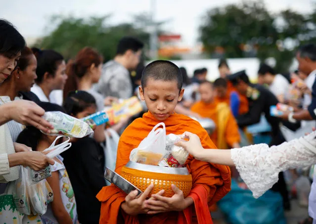 Thais offer food to a Buddhist novice monk during the Mass Alms Giving religious ceremony at the Bangkok Metropolitan Administration City Hall in Bangkok, Thailand, 01 January 2017. Thai people gathered to offer food and essentials to 189 Buddhist monks during the ceremony to mark the New Year. (Photo byRungroj Yongrit/EPA)