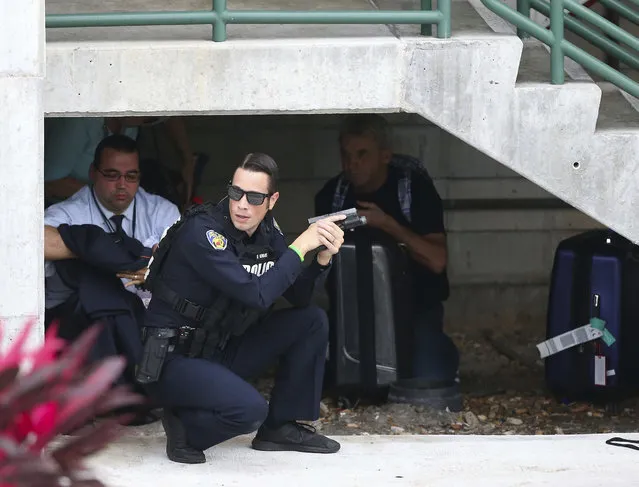 Law enforcement personnel shield civilians outside a garage area at Fort Lauderdale Hollywood International Airport, Friday, January 6, 2017, in Fort Lauderdale, Fla., after a shooter opened fire inside a terminal of the airport, killing several people and wounding others before being taken into custody. (Photo by David Santiago/El Nuevo Herald via AP Photo)